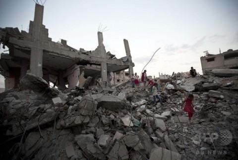 パレスチナ自治区ガザ地区（Gaza Strip）のガザ市（Gaza city）東部シェジャイヤ（Shejaiya）地区で、イスラエルとイスラム原理主義組織ハマス（Hamas）との戦闘で破壊されたがれきと化した建物跡を歩く子どもたち（2014年10月12日撮影）。(c)AFP/MAHMUD HAMS